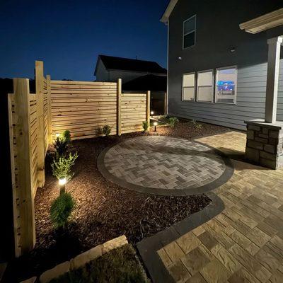 This nighttime view showcases Zamora Design and Build's expertise in creating inviting outdoor spaces with hardscaping, fenci...