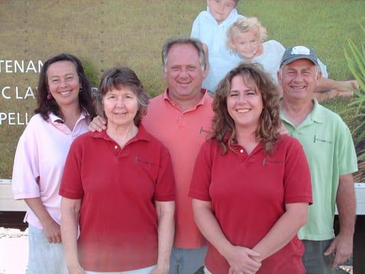 Dell (center) and the Sadler family pose in front of one of their landscaping trucks.