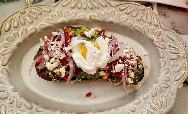 Avocado toast with poached egg, onion, feta, and tomato