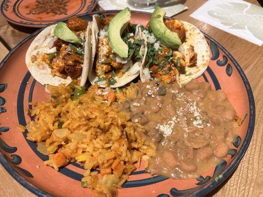 Chicken tacos with avocado, with beams and rice.