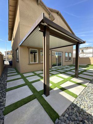 Patio cover with concrete, artificial grass and river rocks.