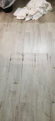 exact same spot in front of bathroom sink in flooring is cracked at a depression in the middle & not all repaired