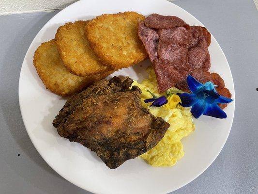 Chicken and scrambled eggs with hash browns with bacon.