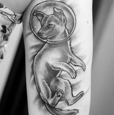 Dog wearing an astronaut helmet in photorealistic black and grey, showing fine detail in the helmet visor and shading on the arm