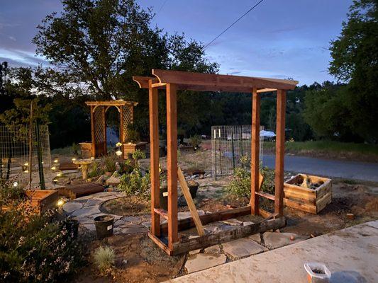 Evening light catching the curve of a garden coming to life -- arbor builds, flagstone paths, and a whole lot of intention.