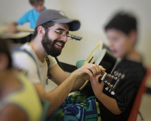 Jon showing a young student how to finger a chord on the guitar.
