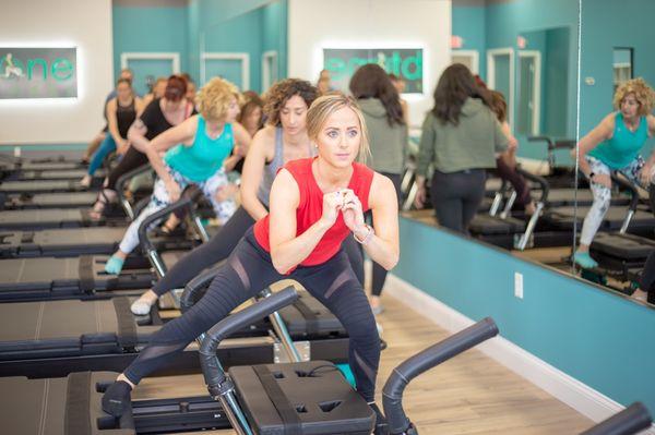 Small group fitness class offering resistance training on a custom designed reformer machine