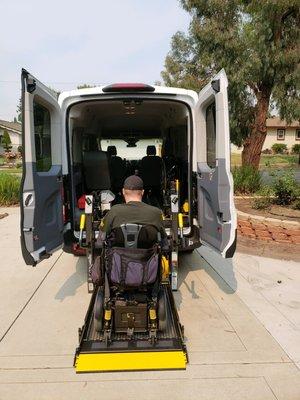 Preparing to load a passenger in his electric wheelchair. Our vans accommodate the wider wheelchairs.