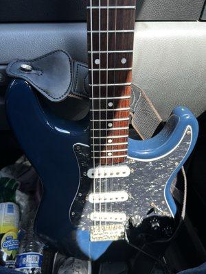 A Squier Stratocaster with a black pearl pick guard, and black knobs.