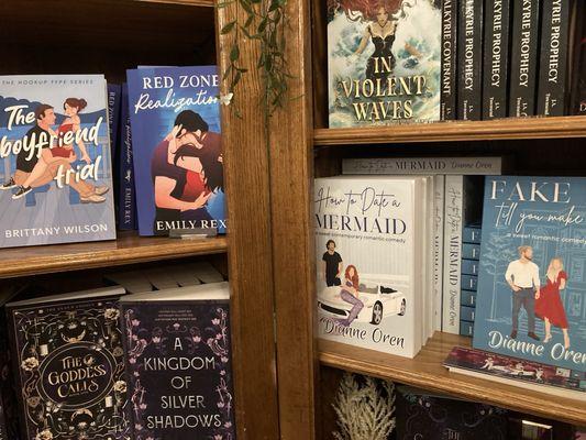 Selection of romance novels face out on wooden bookshelves.