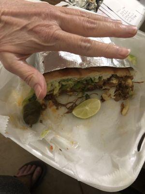 Only 1/2 of what's left of my huge torta birria. Bread was fresh! Probably homemade. Hand for size comparison.