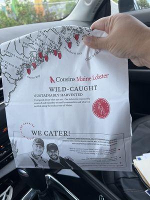 Bag containing lobster roll & bowl of clam chowder