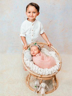 Toddler big brother with his brand new baby sister during a newborn session in studio
