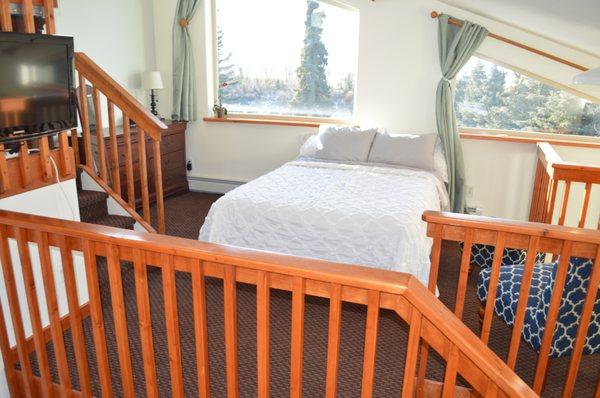 Separated bedroom suite with queen bed, sitting area and satellite flatscreen TV. Blackout curtains in sleeping area