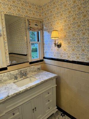 1947 Bathroom with yellow tile trimmed in black walls, and penny tile floor.