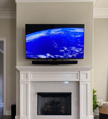 Above fireplace installation with attached soundbar and small A/v equipment in recessed media box.