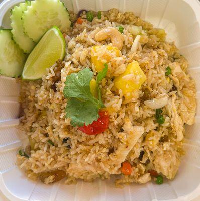 Pineapple fried rice loaded with chicken, cashews, and sweet pineapple chunks, served with fresh cucumbers and a lime wedge.