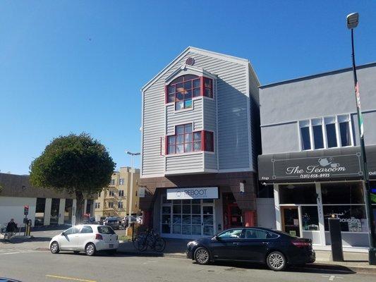 The office is located on the second floor of the building with red trim.