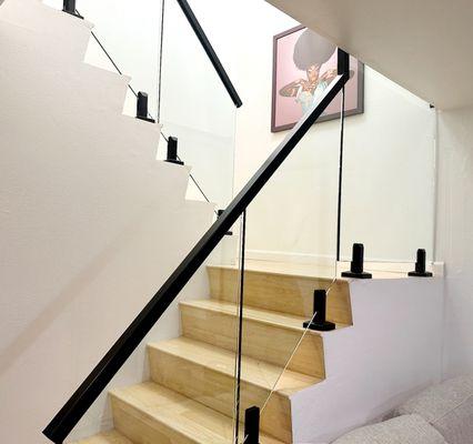 Modern indoor glass railing with matte black spigots -- sleek safety solution for staircases and landings in Los Angeles homes.