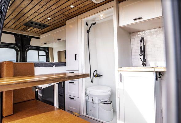 Interior of a Mercedes Benz Sprinter 144" 4x4 High Roof van conversion highlighting an indoor shower, and a full kitchenette.
