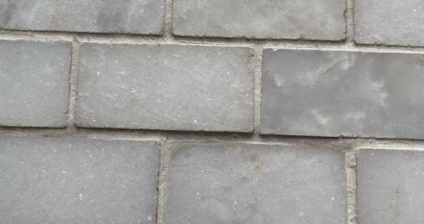 Uneven bathroom floor tiles with edges sticking up.