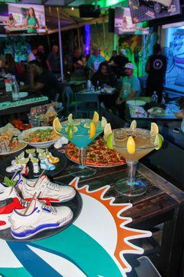Game day at Grails Wynwood with sneaker cocktails, food, and football fans packed in for the perfect sports bar experience.