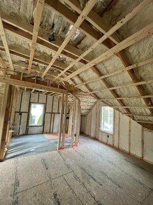 Open & Closed Cell Spray Foam. Under-construction space primed for transformation, featuring exposed framing and comprehensive insulation.