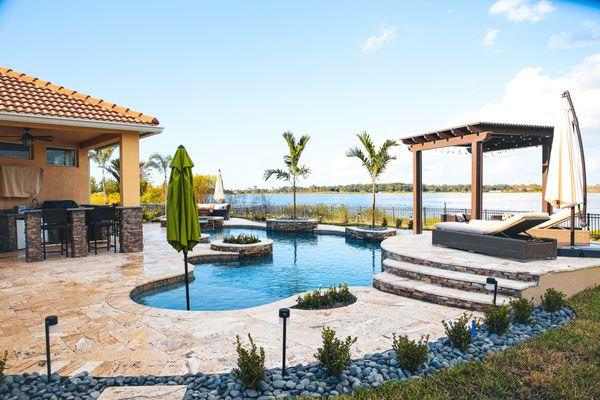 This lagoon-style pool features curved edges, a shallow entry, and an open tropical view.