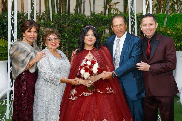 Quinceañera with family after her religious ceremony at garden.