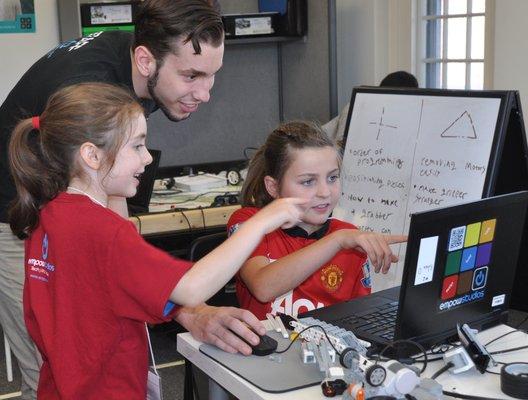 Empow Studios teacher works with two students on their custom robot build.