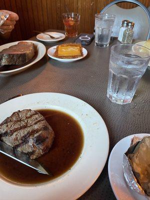 Queen cut prime rib background, filet medium rare, and hashbrowns with cheese and onion and baked potato