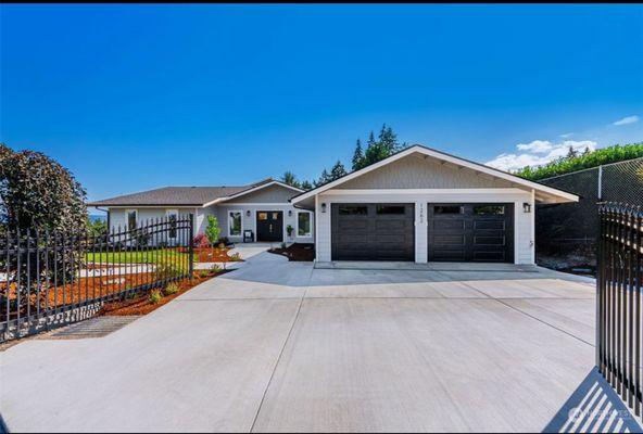 A full exterior transformation featuring new siding, upgraded roofing, a redesigned modern entry, new concrete driveway and walkways, custom