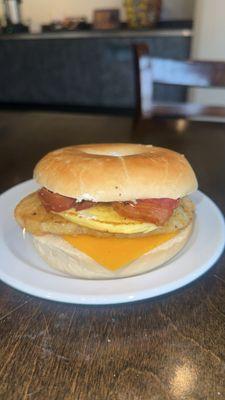 Toasted bagel breakfast sandwich with egg, cheddar cheese, and ham--made fresh and served warm!