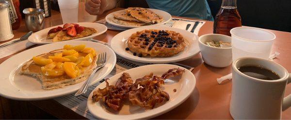 Pancake with peaches, French toast with fresh strawberries, waffle with fresh blueberries, bacon