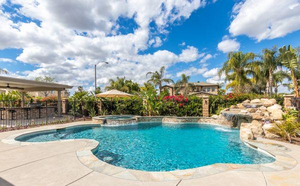 Freeform pool with rock waterfall, raised spas and baja shelf.