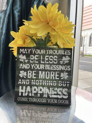 Yellow flowers behind rustic sign, "May your troubles be less and your blessings be more and nothing but happiness come through your door."