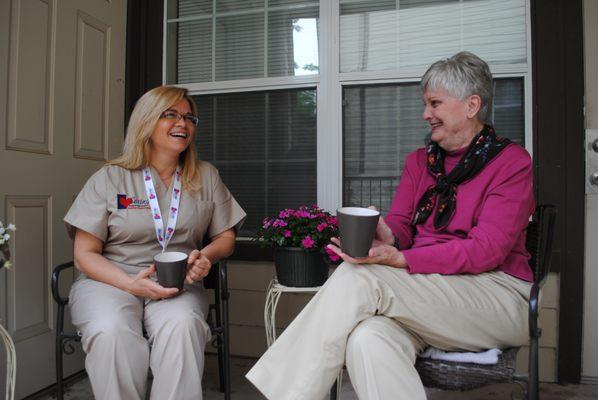 Caring Senior Service caregiver sitting on the porch talking with a client