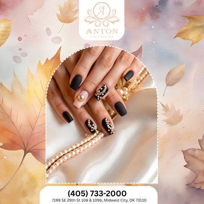 Matte black nails with gold pearls -- sleek and elegant for a modern fall statement. Book your glam look today!