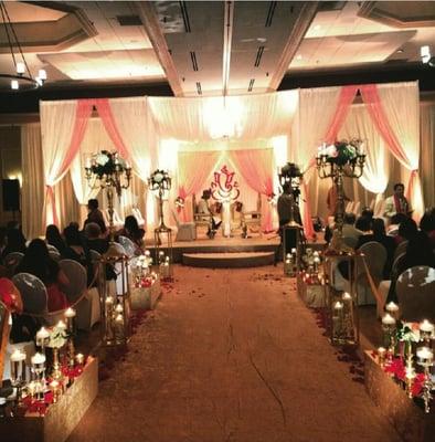 Aisle, double mandap, floral ganesh backdrop, soft amber lighting
Wedding