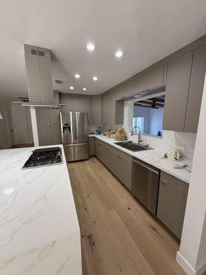 Modern kitchen remodel with custom cabinets, quartz waterfall island, and new hardwood floors.
