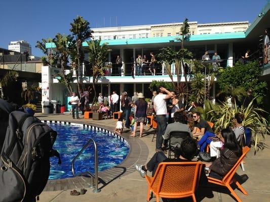 Art enthusiasts crowd the 2nd floor decks and the poolside on a sunny day in the TL.