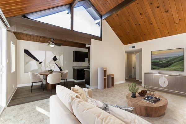 Staged living and dining area with carpeting and hardwood-style vinyl floors.
