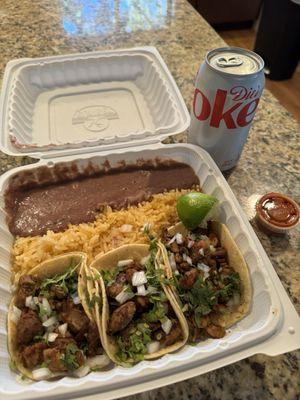 Chicken tacos with rice and beans, drink, and hot sauce