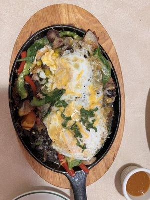 Breakfast skillet, over medium eggs, sausage, black beans, sliced red and green bell peppers and more.