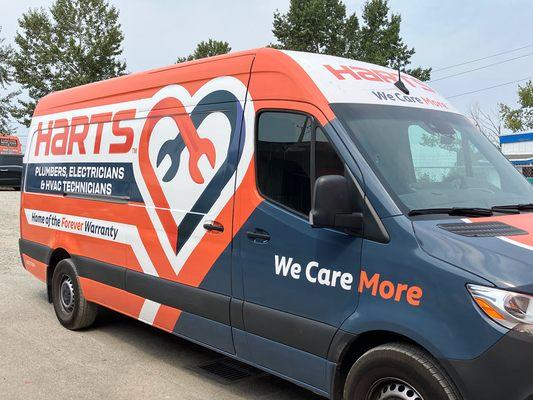 Side view of Harts van with bold "We Care More" messaging.