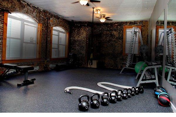 Back half of the studio showing off the power rack, smith machine, battle ropes, kettlebells, treadmill, rower, bike, and more.