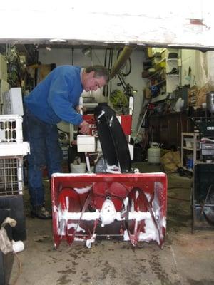 Stan, owner of Yard & Garden Equipment Repair & Servicing, repairing a snow blower in his work shop.