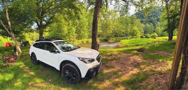Tent campsite by water with car for reference