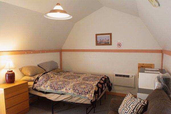Inside of cabin looking at the bed, AC unit and back wall.