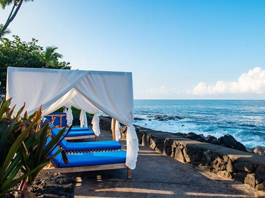 Oceanfront pool cabanas overlooking the clear blue Pacific Ocean